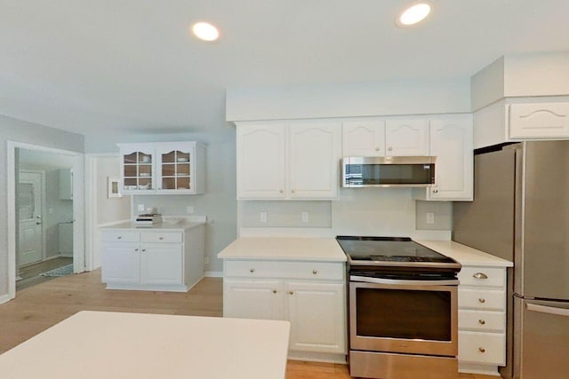 kitchen featuring recessed lighting, stainless steel appliances, light wood-style flooring, light countertops, and white cabinets
