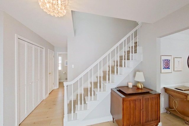 staircase featuring wood finished floors and a notable chandelier