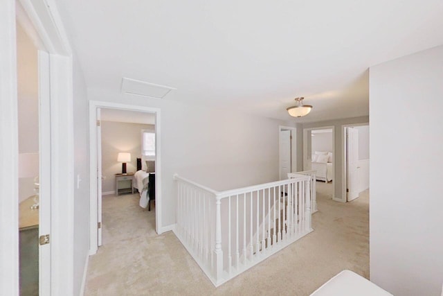 corridor featuring attic access, light carpet, and an upstairs landing