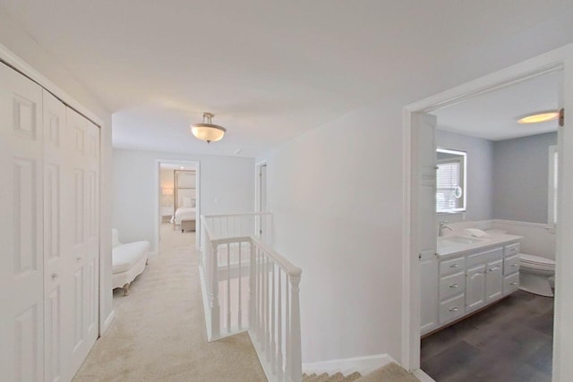 hall featuring an upstairs landing and a sink