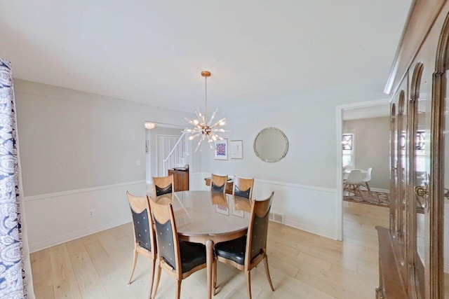 dining room with a chandelier, light wood-type flooring, and visible vents