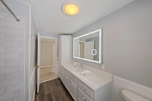 bathroom with toilet, vanity, walk in shower, and wood finished floors