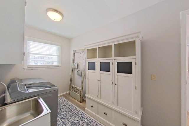 laundry room with washer / clothes dryer, a sink, light wood-style floors, baseboards, and cabinet space
