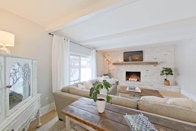 living room featuring beamed ceiling, baseboards, and a fireplace