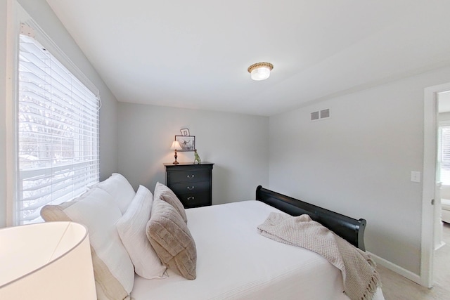 bedroom featuring visible vents, baseboards, and light carpet