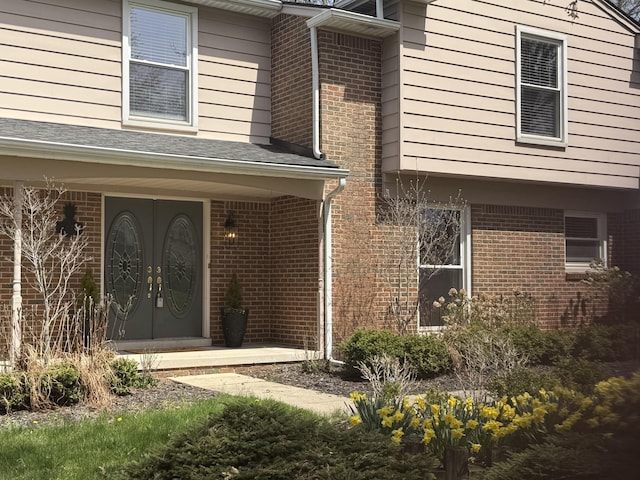 view of exterior entry with covered porch and brick siding