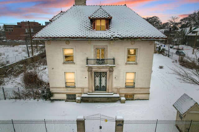 snow covered back of property featuring a balcony