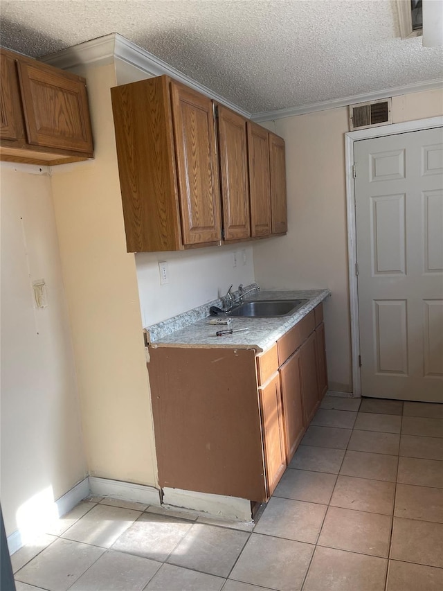 kitchen featuring a textured ceiling, crown molding, light tile patterned floors, and sink