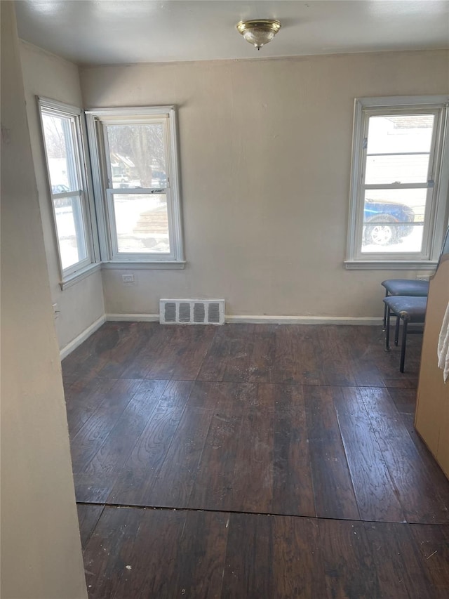 spare room with plenty of natural light and dark wood-type flooring