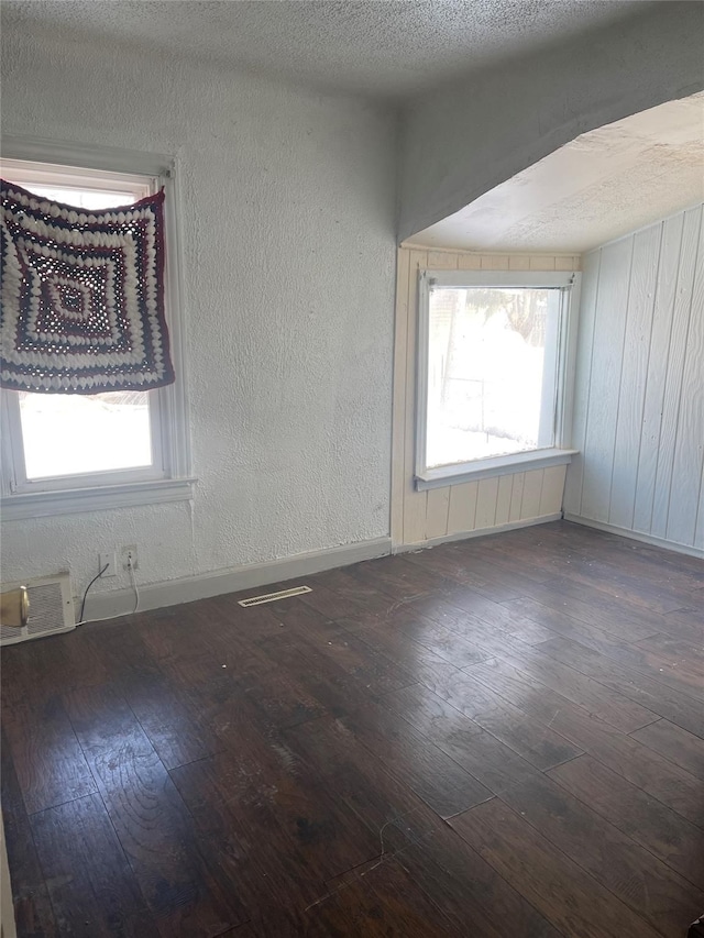 spare room featuring dark hardwood / wood-style flooring and a textured ceiling