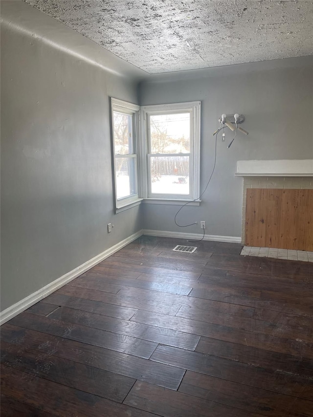 unfurnished room with a textured ceiling and dark hardwood / wood-style flooring