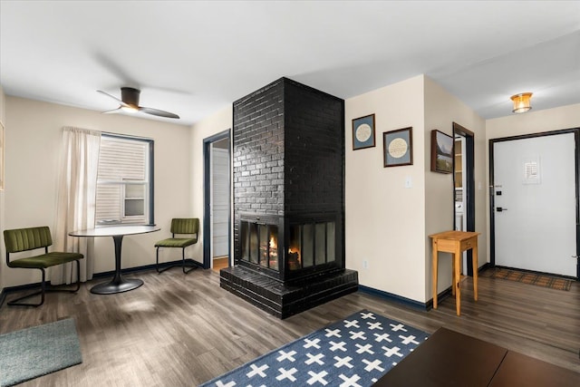 living room featuring ceiling fan, dark hardwood / wood-style flooring, and a brick fireplace