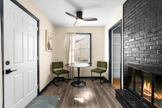 sitting room featuring ceiling fan, a fireplace, and hardwood / wood-style flooring