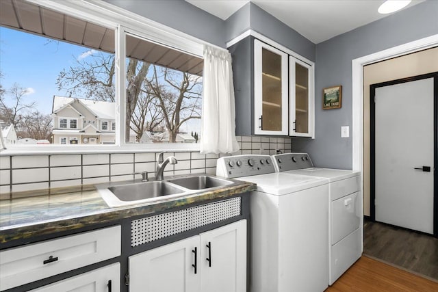 laundry room featuring washing machine and dryer, dark hardwood / wood-style flooring, sink, and cabinets