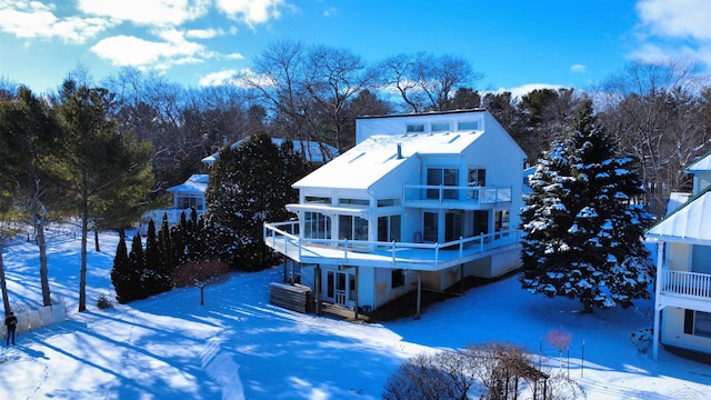 snow covered back of property with a deck