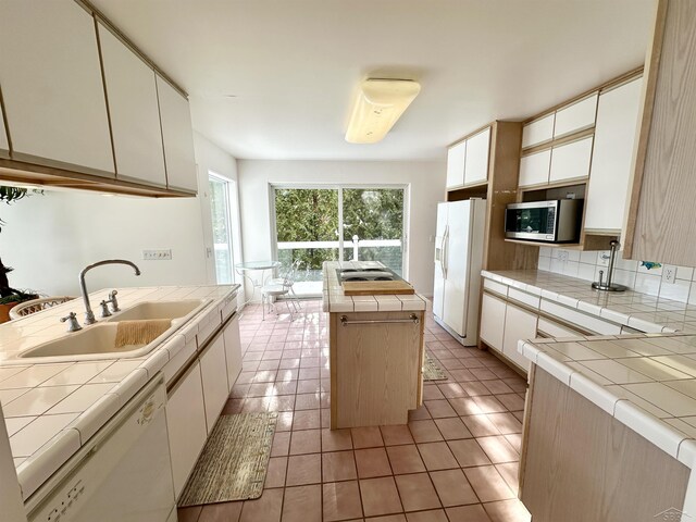 kitchen with white appliances, tile countertops, and a kitchen island with sink