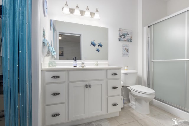 bathroom with tile patterned flooring, ceiling fan, toilet, a shower with door, and vanity