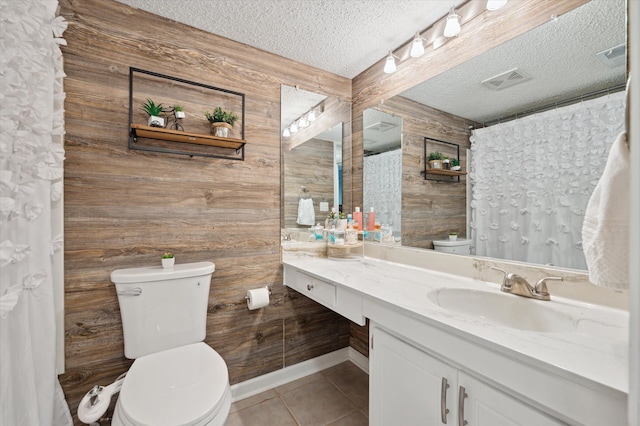 bathroom with tile patterned floors, toilet, a textured ceiling, and wood walls