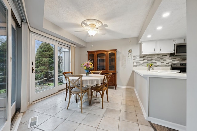 dining room featuring ceiling fan, sink, a textured ceiling, and light tile patterned floors