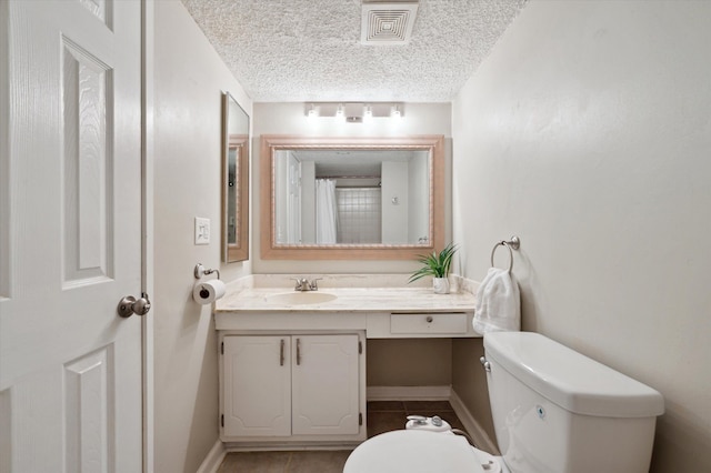 bathroom featuring tile patterned floors, vanity, toilet, and a textured ceiling