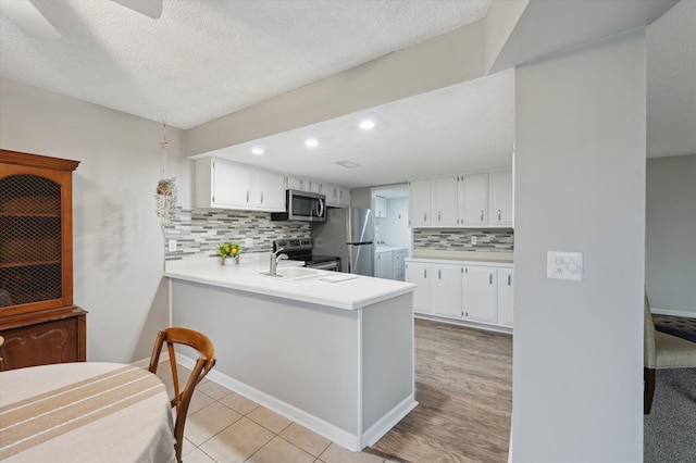 kitchen featuring white cabinetry, appliances with stainless steel finishes, kitchen peninsula, and sink