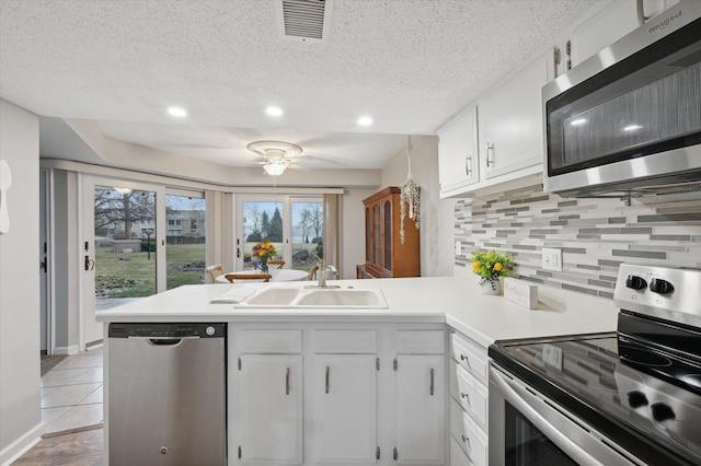 kitchen with white cabinetry, appliances with stainless steel finishes, kitchen peninsula, and sink