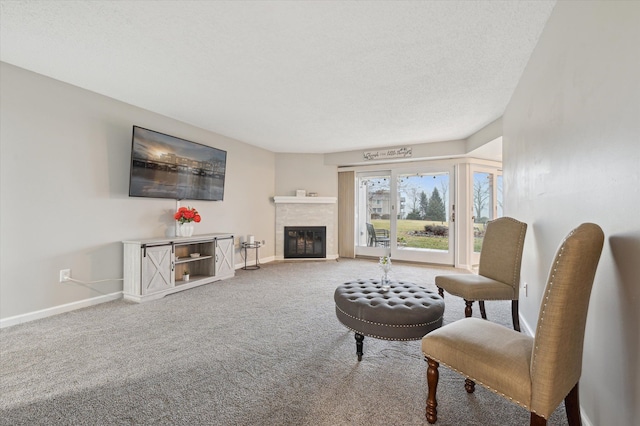 living room with a tile fireplace, a textured ceiling, and carpet flooring