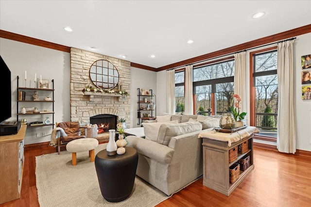 living room with a fireplace, ornamental molding, and light hardwood / wood-style flooring