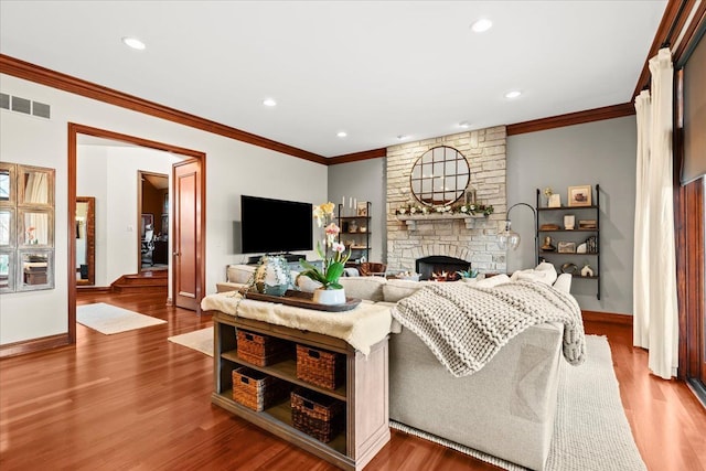 living room with a stone fireplace, crown molding, and wood-type flooring