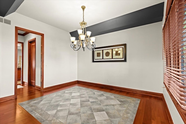 empty room featuring dark wood-type flooring and a chandelier