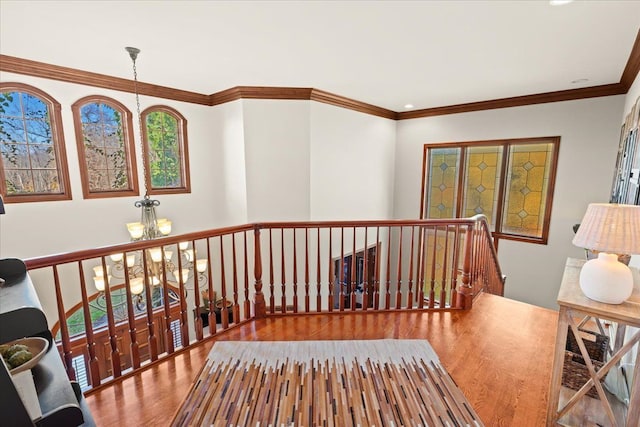 hall with hardwood / wood-style flooring, crown molding, and a chandelier