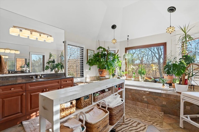 bathroom featuring a healthy amount of sunlight, vanity, lofted ceiling, and tiled bath