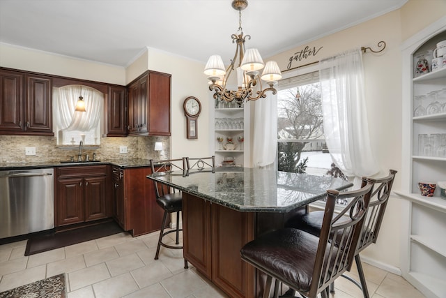 kitchen with sink, a kitchen breakfast bar, dark stone countertops, stainless steel dishwasher, and a notable chandelier