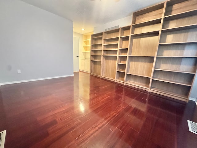 interior space featuring visible vents, baseboards, and dark wood finished floors