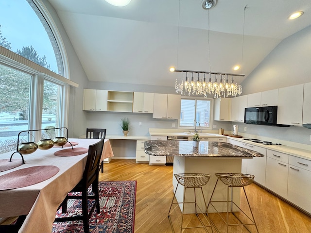 kitchen featuring light wood-type flooring, white cabinetry, a kitchen island, and black microwave