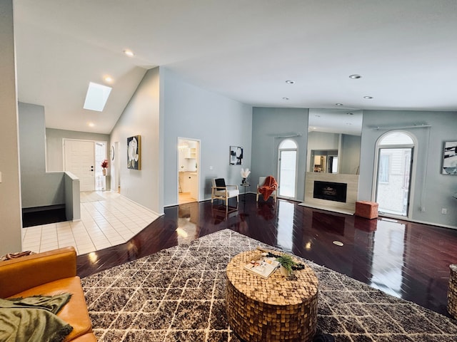 living room with lofted ceiling with skylight, a fireplace, wood finished floors, and recessed lighting