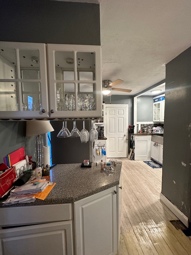 kitchen with white cabinetry, a textured ceiling, ceiling fan, and light wood-type flooring