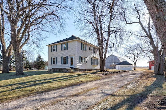 colonial home with a front yard, a garage, and an outbuilding