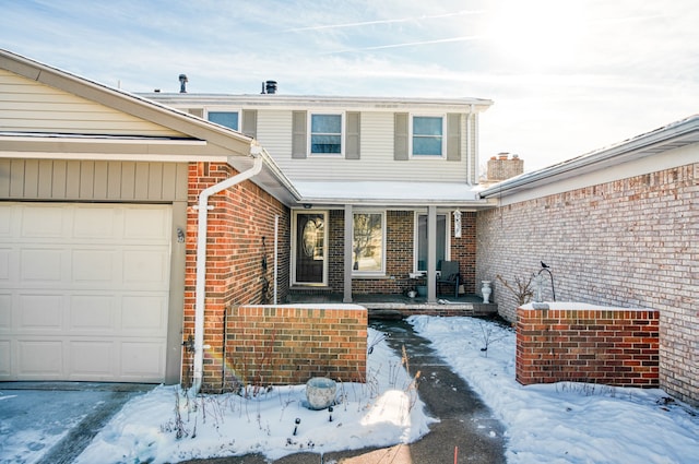 snow covered property entrance with a garage