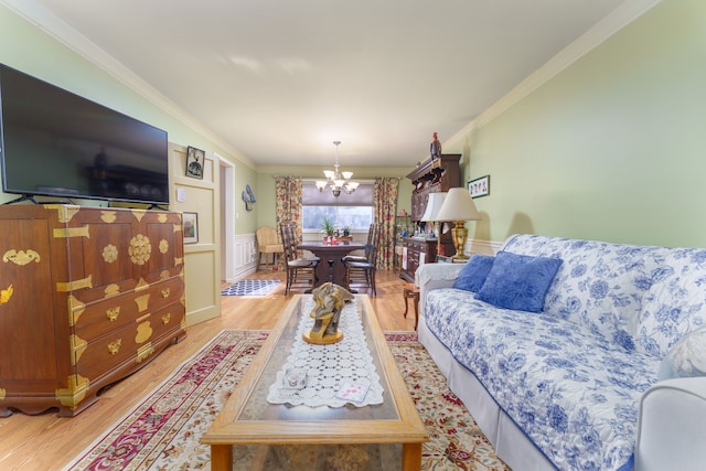 living room featuring crown molding, a chandelier, and light wood-type flooring