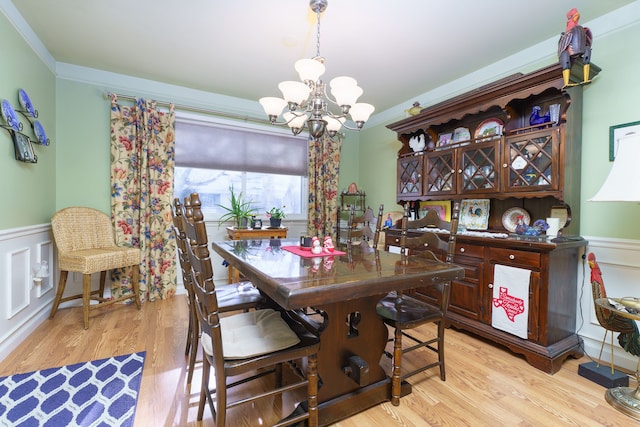 dining space with ornamental molding, a notable chandelier, and light hardwood / wood-style flooring