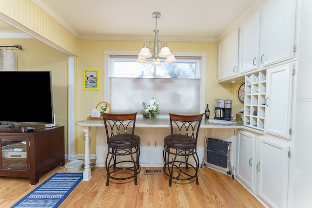 dining space with an inviting chandelier, crown molding, and light wood-type flooring