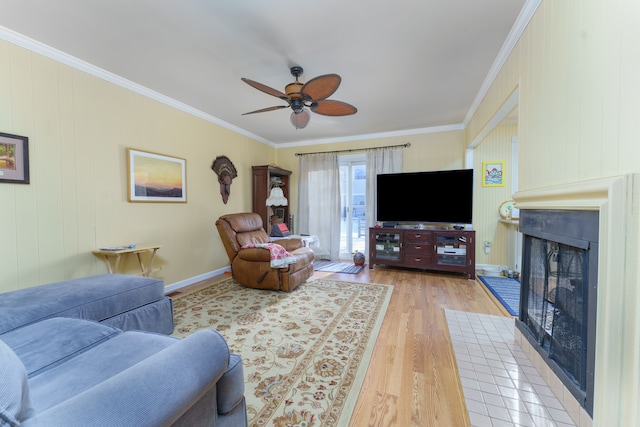 living room featuring ceiling fan, ornamental molding, a fireplace, and hardwood / wood-style floors