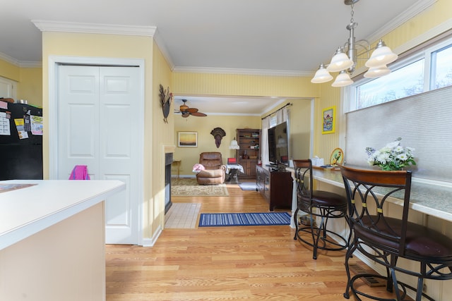 dining space featuring ornamental molding, ceiling fan with notable chandelier, and light hardwood / wood-style flooring