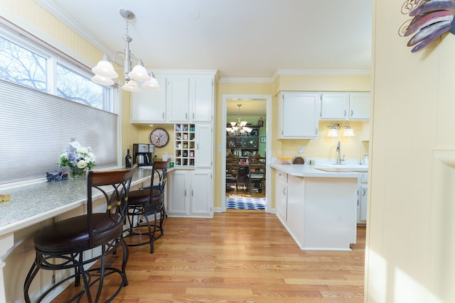 kitchen with hanging light fixtures, white cabinetry, a chandelier, and light hardwood / wood-style floors