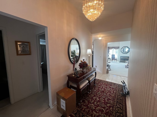 corridor with a notable chandelier, baseboards, and light tile patterned floors