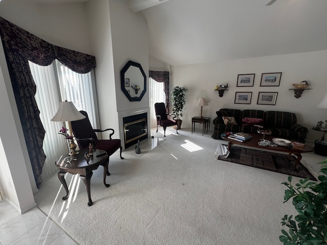 carpeted living area with plenty of natural light, high vaulted ceiling, and a glass covered fireplace