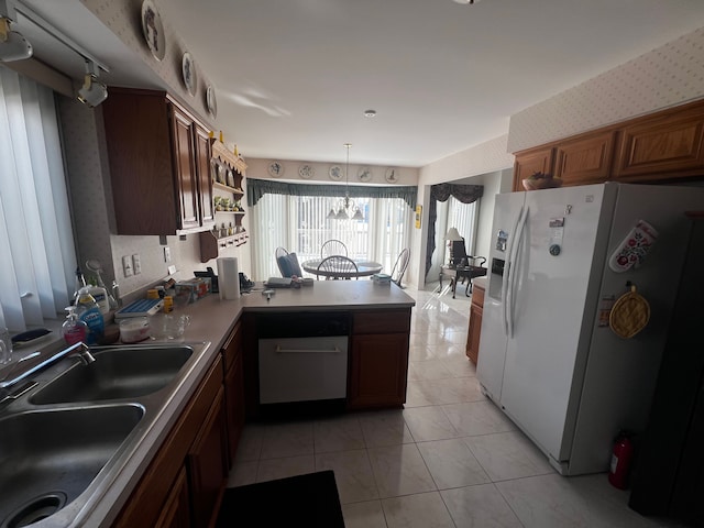 kitchen with wallpapered walls, light tile patterned floors, white refrigerator with ice dispenser, a peninsula, and a sink