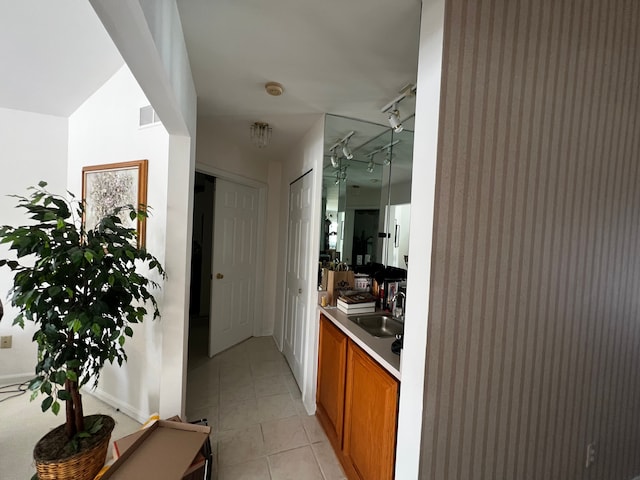 corridor featuring light tile patterned flooring, a sink, and track lighting