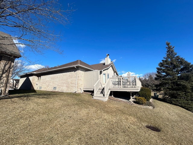 back of house featuring a yard, brick siding, a chimney, and a wooden deck